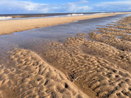 Foto de Hermoso paisaje natural playa de arena con dunas de arena y marea baja océano agua salada bajo el cielo azul con nubes en primavera en Winterton Norfolk East Anglia Reino Unido - Imagen libre de derechos