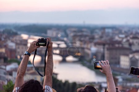 Large tourist crowd on Piazzale Michelangelo enjoying sunset over Florence, Italy