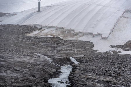 Téléchargez les photos : Une grande bâche de neige protégeant la glace du glacier Hintertux dans les Alpes, une cascade d'eau de fonte coule dans la roche, Autriche - en image libre de droit