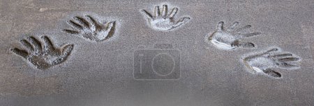 Foto de Five hand prints relief in concrete pavement filled with water from rain. Background and wallpaper texture. Copy space - Imagen libre de derechos