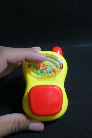 Foto de Una foto de un lindo juguete talky amarillo en la mano - Imagen libre de derechos