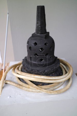 ein Foto einer künstlichen Stupa aus Zement. Für die Außendekoration. schwarz, mit einem Wasserschlauch umwickelt