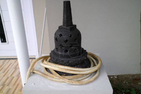 ein Foto einer künstlichen Stupa aus Zement. Für die Außendekoration. schwarz, mit einem Wasserschlauch umwickelt