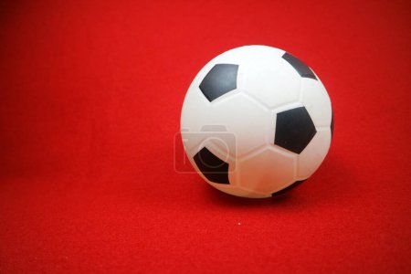 Téléchargez les photos : Une photo d'une petite boule en caoutchouc jouet blanche et noire. Fond rouge - en image libre de droit