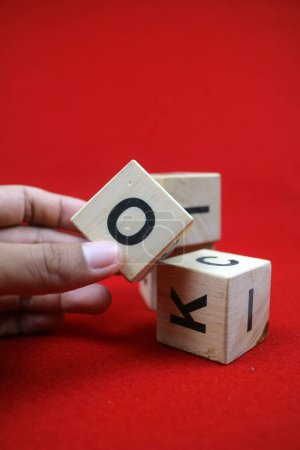 Téléchargez les photos : Un jouet éducatif empilable en bois avec des chiffres et des lettres. Fond rouge - en image libre de droit