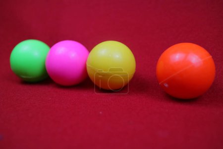 Téléchargez les photos : Photo of Several toy balls are pink, yellow, green and orange on a red background - en image libre de droit
