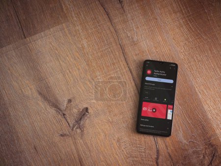 Foto de Lod, Israel - July 16,2023: Twilio Authy Authenticator app play store page on smartphone on wooden background. Top view flat lay with copy space. - Imagen libre de derechos