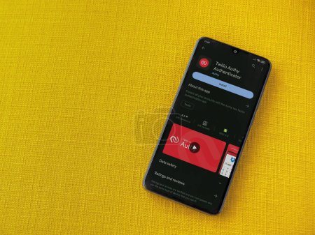 Foto de Lod, Israel - July 16,2023: Twilio Authy Authenticator app play store page on smartphone on a yellow fabric background. Top view flat lay with copy space. - Imagen libre de derechos
