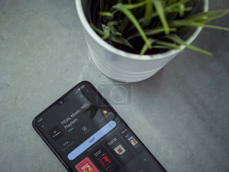 Foto de Lod, Israel - July 16,2023: Modern workspace with smartphone with TIDAL Music app play store page on marble background. Close up top view flat lay. - Imagen libre de derechos