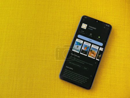 Photo for Lod, Israel - July 16,2023: Insta360 app play store page on smartphone on a yellow fabric background. Top view flat lay with copy space. - Royalty Free Image