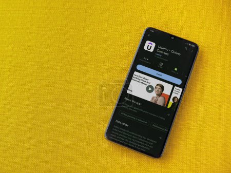 Foto de Lod, Israel - July 16,2023: Udemy app play store page on smartphone on a yellow fabric background. Top view flat lay with copy space. - Imagen libre de derechos
