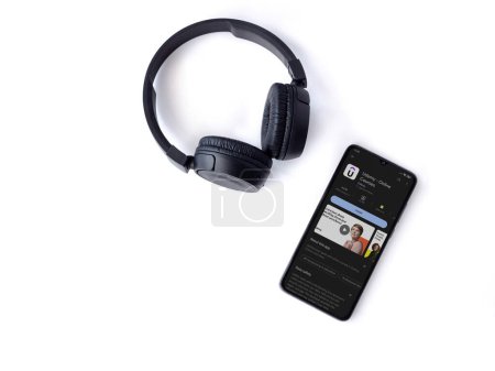 Foto de Lod, Israel - July 16,2023: Smartphone with Udemy app play store page and wireless headphones on white background. Top view flat lay with copy space. - Imagen libre de derechos