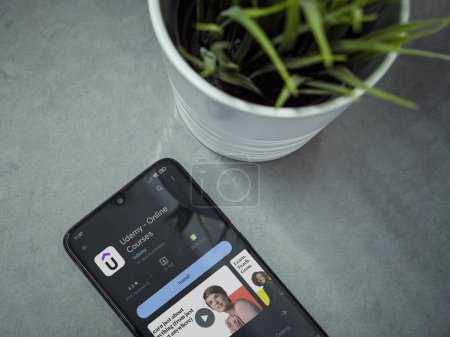 Foto de Lod, Israel - July 16,2023: Modern workspace with smartphone with Udemy app play store page on marble background. Close up top view flat lay. - Imagen libre de derechos