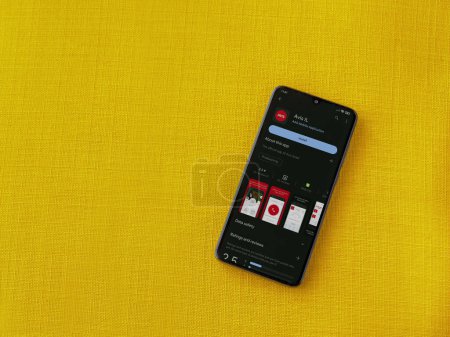 Photo for Lod, Israel - July 16,2023: Avis IL app play store page on smartphone on a yellow fabric background. Top view flat lay with copy space. - Royalty Free Image