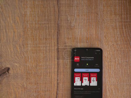Photo for Lod, Israel - July 16,2023: Avis Corporate app play store page on smartphone on wooden background. Top view flat lay with copy space. - Royalty Free Image