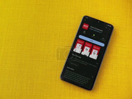 Photo for Lod, Israel - July 16,2023: Avis Corporate app play store page on smartphone on a yellow fabric background. Top view flat lay with copy space. - Royalty Free Image