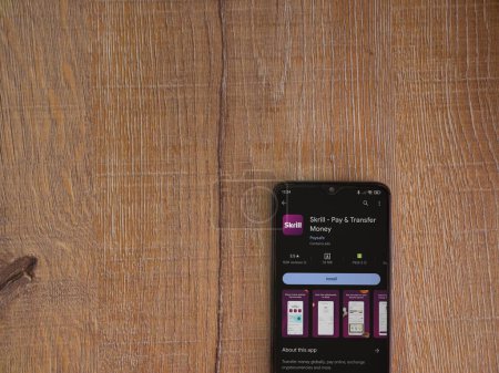 Photo for Lod, Israel - July 16,2023: Skrill app play store page on smartphone on wooden background. Top view flat lay with copy space. - Royalty Free Image