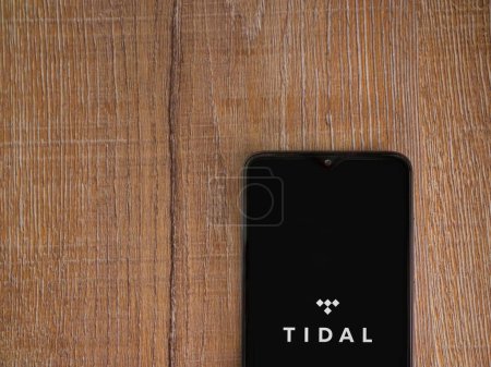 Foto de Lod, Israel - 16 de julio de 2023: Pantalla de lanzamiento de la aplicación TIDAL Music en el teléfono inteligente sobre fondo de madera. Vista superior plano con espacio de copia. - Imagen libre de derechos