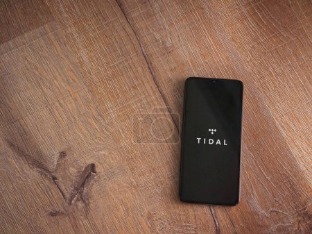 Foto de Lod, Israel - 16 de julio de 2023: Pantalla de lanzamiento de la aplicación TIDAL Music en el teléfono inteligente sobre fondo de madera. Vista superior plano con espacio de copia. - Imagen libre de derechos