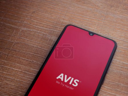 Photo for Lod, Israel - July 16,2023: Avis IL app launch screen on smartphone on wooden background. Top view flat lay with copy space. - Royalty Free Image