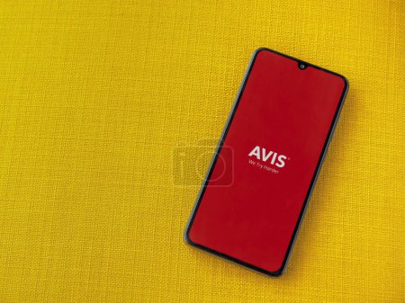 Photo for Lod, Israel - July 16,2023: Avis IL app launch screen on smartphone on yellow fabric background. Top view flat lay with copy space. - Royalty Free Image