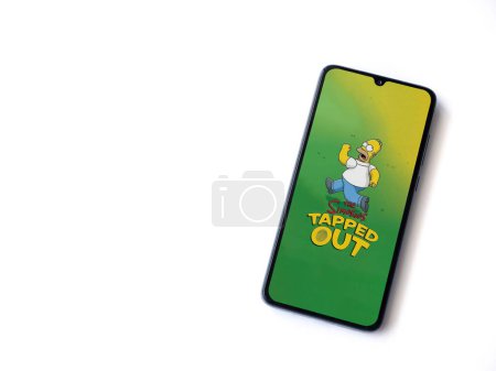 Photo for Lod, Israel - July 16,2023: The Simpsons Tapped Out app launch screen on smartphone on white background. Top view flat lay with copy space. - Royalty Free Image