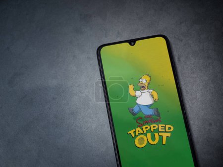 Photo for Lod, Israel - July 16,2023: The Simpsons Tapped Out app launch screen on smartphone on dark marble stone background. Top view flat lay with copy space. - Royalty Free Image