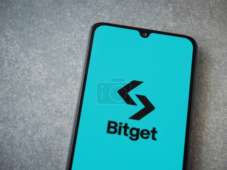 Téléchargez les photos : Lod, Israël - 16 juillet 2023 : Écran de lancement de l'application Bitget sur smartphone sur fond de pierre céramique. Vue du dessus plat avec espace de copie. - en image libre de droit