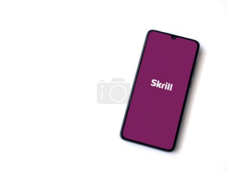 Photo for Lod, Israel - July 16,2023: Skrill app launch screen on smartphone on white background. Top view flat lay with copy space. - Royalty Free Image
