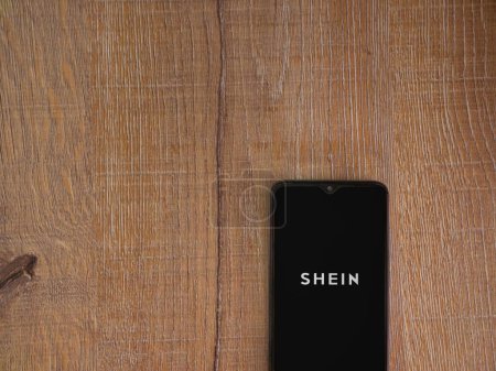 Foto de Lod, Israel - 16 de julio de 2023: Pantalla de lanzamiento de la aplicación Shein en el teléfono inteligente sobre fondo de madera. Vista superior plano con espacio de copia. - Imagen libre de derechos