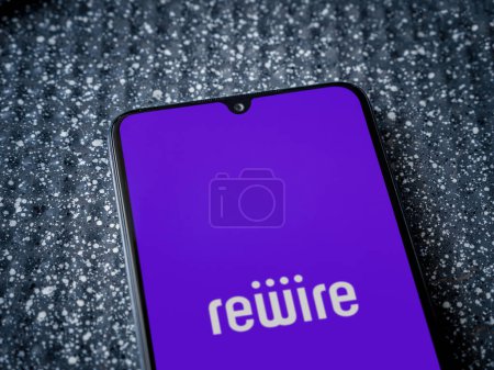 Photo for Lod, Israel - July 16,2023: Rewire app launch screen on smartphone on metallic background. Close up top view flat lay. - Royalty Free Image