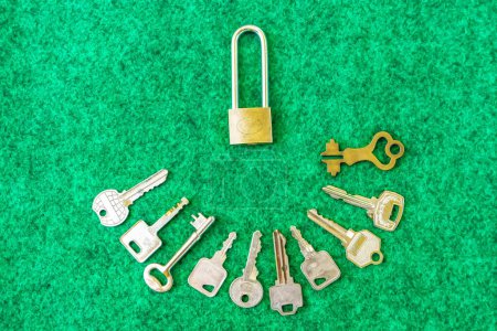 Photo for Brass Padlock and many types of keys on green carpet background. - Royalty Free Image