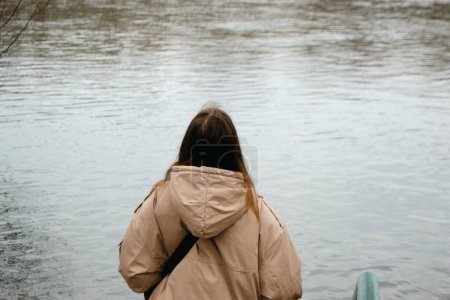 Una mujer con el pelo castaño largo cerca del río en primavera. Foto de alta calidad