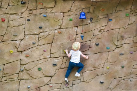Photo for The boy is engaged in rock climbing. Climbing harness safety sports equipment. Rope amusement city park, obstacle course. Kids childrens attraction center. High quality photo - Royalty Free Image