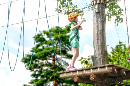 Adventure climbing high wire park - child on course in mountain helmet and safety equipment. High quality photo