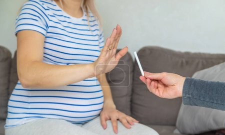 Téléchargez les photos : La femme enceinte refuse de fumer. Concentration sélective. Chez moi. - en image libre de droit