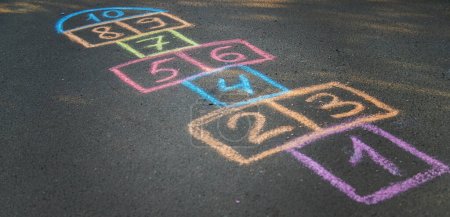 Backyard classics on an asphalt floor with chalk drawn numbers and squares. Selective focus. nature