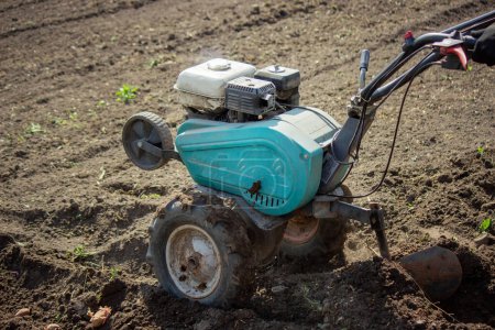 un agricultor macho trabaja en el campo en una caminata detrás de un tractor, arada la tierra con un arado