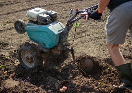 un agricultor macho trabaja en el campo en una caminata detrás de un tractor, arada la tierra con un arado