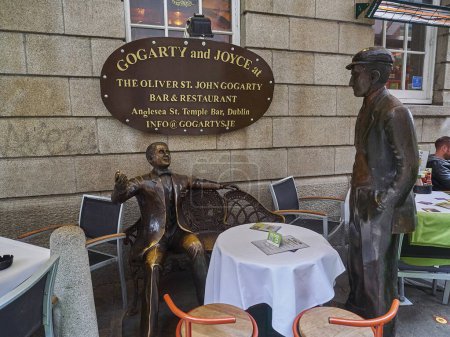 Foto de Dublín, Irlanda - 09 25 2015: Estatua de Gogarty y Joyce en Anglesea Street en medio de mesas y sillas de un restaurante. - Imagen libre de derechos