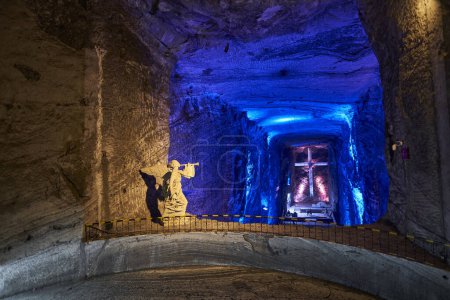 Foto de Zipaquira, Colombia - 04 12 2019: escultura de ángel y cruz gigante en la catedral católica de Zipaquira está construido en los túneles de una mina de sal subterránea y artísticamente iluminado con luz de colores. - Imagen libre de derechos