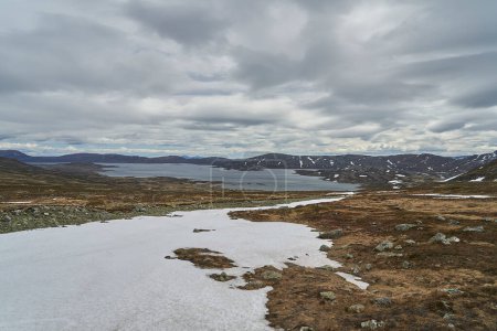 Téléchargez les photos : Lac dans le paysage montagneux de Jotunheimen en Norvège, avec des sommets enneigés en arrière-plan, une destination de voyage populaire pour la randonnée. - en image libre de droit