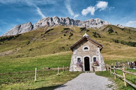 small stone chapel in the french alps in the summer with green meadow and mountains