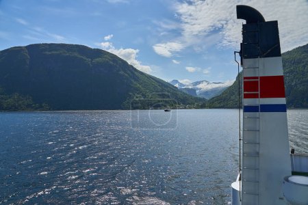 Die typisch norwegische Autofähre überquert an einem sonnigen Tag einen wunderschönen Fjord zwischen den Bergen und befördert Passagiere und Autos auf dem Weg nach Geiranger,