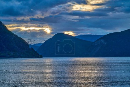 sunset at the beautiful Sognefjord in Norway, with water ripples and dramatic sky.