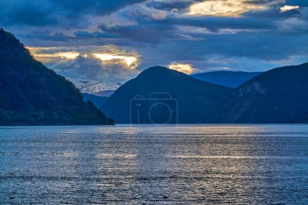 sunset at the beautiful Sognefjord in Norway, with water ripples and dramatic sky.