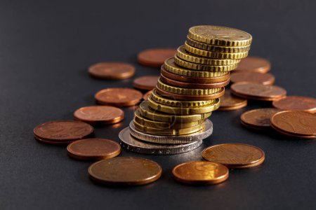 Téléchargez les photos : Tilted stack of coins close-up on a blurred dark background. - en image libre de droit