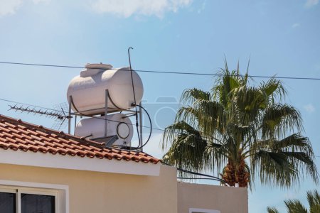 Ein solarbeheizter Wasserkocher auf dem Dach eines Hauses mit blauem Himmel im Hintergrund.