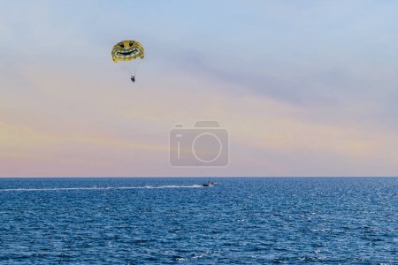 Photo for Flying parasailing parachute tied to a motorboat in the sea. Beautiful seascape in the evening with tourist entertainment. - Royalty Free Image