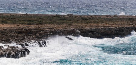 Ocean waves crashing against rocks in a storm. Wind-driven waves crash against a rocky seashore.